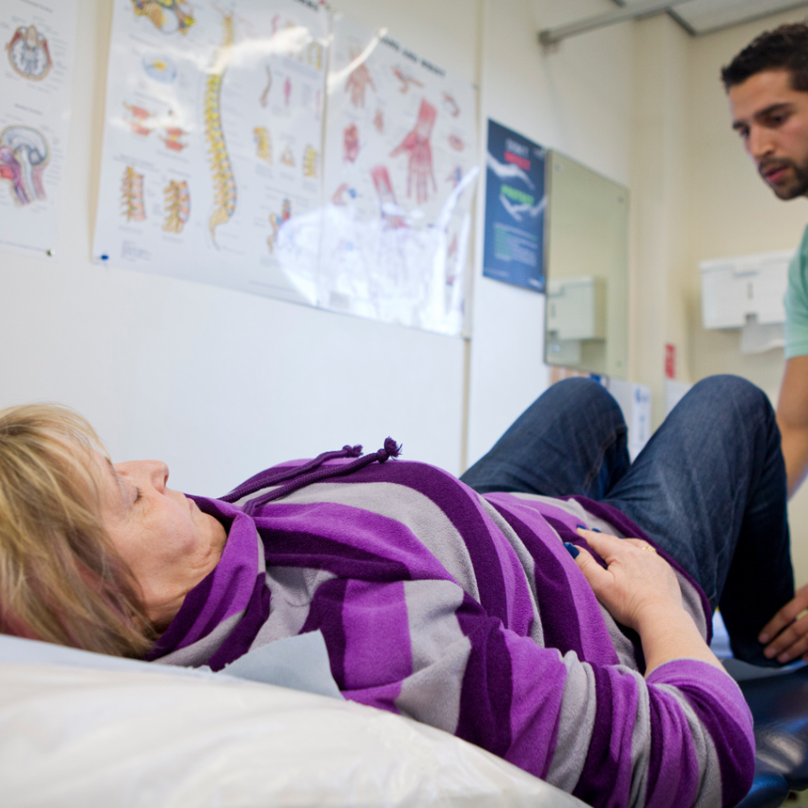 Physiotherapist Holding The Ankles Of A Patient Whilst They Lie On A Medical Bed